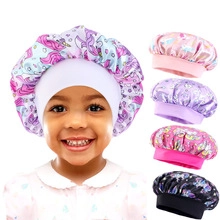 Detailed close-up of a satin kids sleeping cap with colorful unicorn prints and pink ribbon