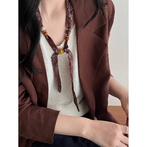 Detail of bohemian paisley fabric necklace with ethnic wooden beads on a model