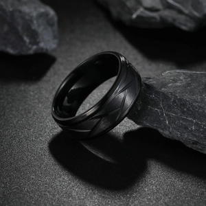 Macro view of 8mm black stainless steel ring with slanted textured finish on rock