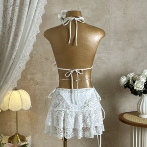 Detailed view of white lace bikini set with ruffled skirt and delicate waist chain detail