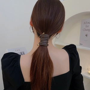 Detail of dark brown leather hair wrap with gold metal caps on a low ponytail hairstyle