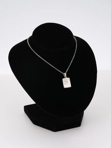 Detail of square shell pendant with engraved letter B on stainless steel chain