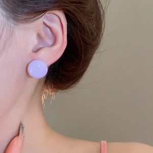 Close-up of lavender purple button stud earrings worn by a model for a soft aesthetic