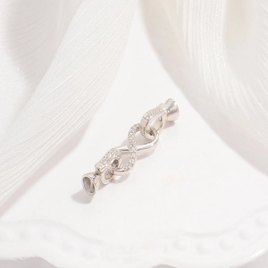 Macro detail of silver S925 infinity jewelry clasp with micro-set zircon on silk background