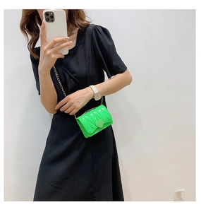 Detail view of heart-shaped buckle and textured neon green patent leather kids bag