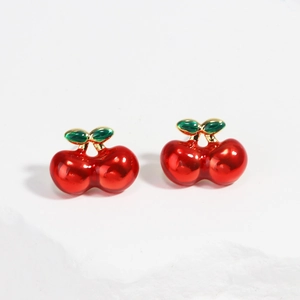 Détail de boucles d'oreilles cerises rouges avec feuilles en émail vert et tiges dorées