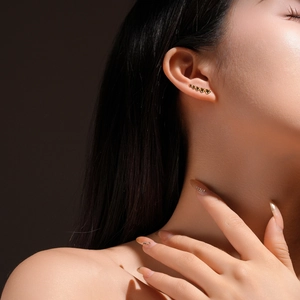 Close-up of gold five-heart ear crawler earring on model featuring polished finish