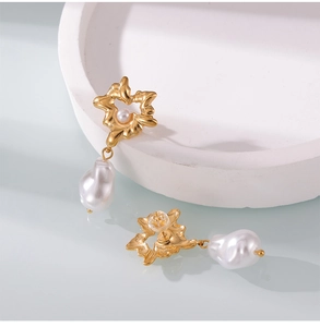Macro view of gold plated titanium earrings with irregular metal flowers and baroque pearls