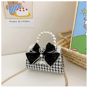 Close-up of girls houndstooth handbag with pearl handle, black bow and gold chain strap