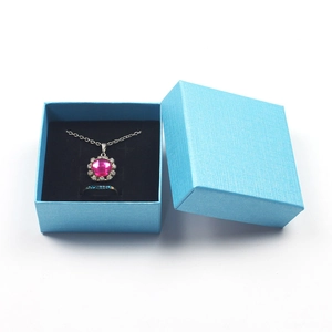 Close-up of sky blue textured jewelry gift box with necklace and ring inside