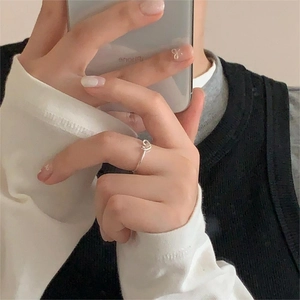 Close-up of a minimalist 925 silver overlapping heart ring worn on a finger