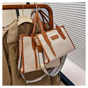 Detail of canvas tote bags with brown leather trim and striped wide shoulder strap