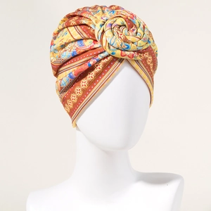 Bohemian women's head wrap in warm orange with a floral paisley pattern and large rose knot