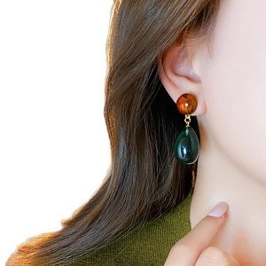 Asymmetric resin drop earrings in amber and dark green featuring vintage aesthetic