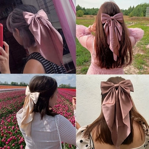 Oversized satin bow hair clip with long ribbons in four colors shown on various hairstyles