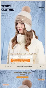 Detail of warm winter knitted beanie with ear flaps and fluffy pom-pom on snowy background