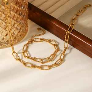 Close-up of golden hammered cross chain necklace with elegant glass and wood background