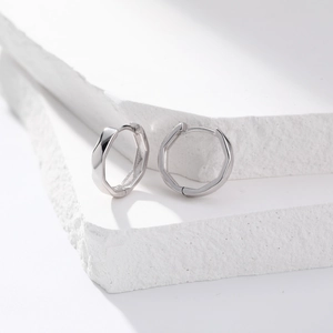 Macro shot of silver octagonal geometric earrings displayed on natural white stone