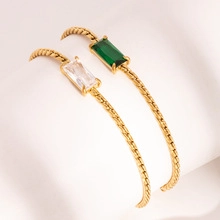 Macro shot of twisted gold bangles with emerald green and white zircon rectangular stones