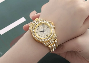 Dettaglio di un orologio al quarzo dorato di lusso con strass lucenti al polso della modella