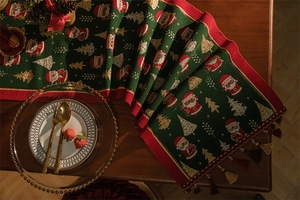 Detailed view of green jacquard Christmas table runner with Santa motifs and gold tassels