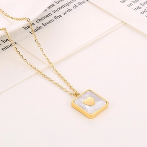 Macro-opname van vierkante witte schelphanger met gouden hart aan een fijne ketting