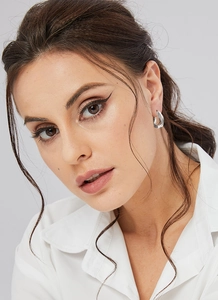 Close-up of minimalist silver egg-shaped earrings with a smooth polished finish on a model