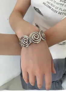 Close-up of wide silver spiral cutout cuff bracelet worn by model on wrist