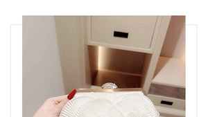 Detail of white pleated evening clutch featuring a sparkling rhinestone clasp and metal frame