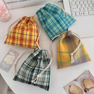 Macro detail of four plaid drawstring storage bags in cotton linen fabric for organizing