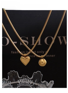 Detailed view of gold snake chain necklaces with solid heart and ball pendants