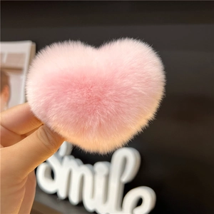 Close-up of a soft pink heart-shaped faux fur hair clip held in hand for hair styling