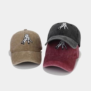 Détail de la broderie main sur des casquettes en coton lavé kaki, noir et bordeaux