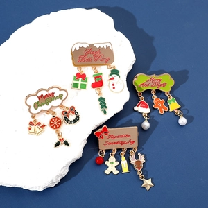Detailed view of enamel Christmas brooches with festive charms on a white textured stone