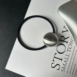 Close-up of black high-elastic hair tie featuring a spherical brushed alloy metal accent