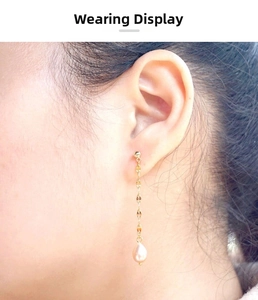 Close-up of elegant long tassel earrings with golden chains and teardrop freshwater pearls