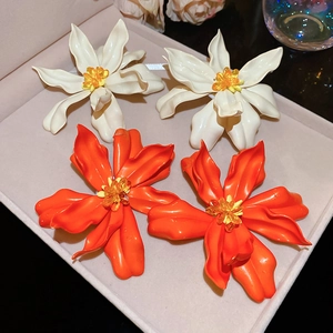 Macro shot of large white and orange acrylic flower earrings on a pink jewelry tray