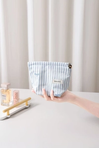 Détail d'une trousse à maquillage rayée bleue avec broderie et tirette fleurie