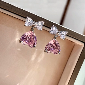 Elegant pink heart gemstone earrings with bow detail on a jewelry box edge
