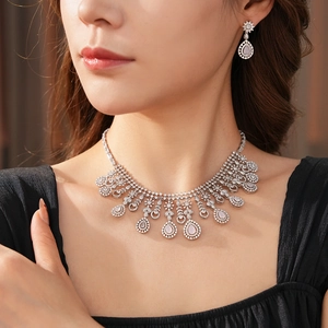 Close-up of elegant necklace and earrings set with zircon flowers and pink teardrops