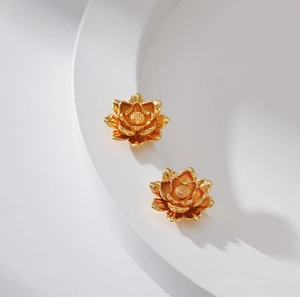 Macro detail of 18K gold plated lotus earrings with textured petals on white background