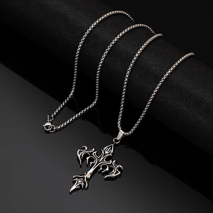 Macro shot of silver metal cross pendant with embossed floral patterns and box chain