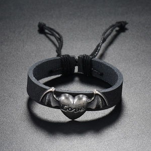 Detail of black leather punk bracelet with winged heart metal charm and Love engraving