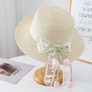 Detail of raffia straw hat featuring white lace ribbon and pink tulip floral charms