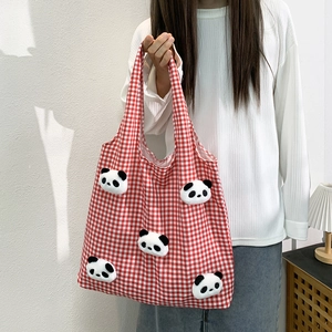 Detail of red checkered canvas tote bag with 3D panda plush dolls held by a model