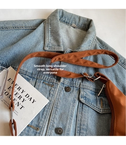 Detail of adjustable long shoulder strap and smooth silver zipper on caramel nylon bag
