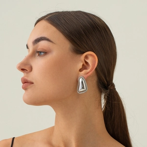 Detailed view of triangular silver earring with rope textured edge on a model's ear