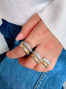 Close-up of stacked 18K gold irregular rings and silver zircon-inlaid bands on fingers