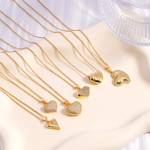 Collection of golden heart pendant necklaces with zircons on a white ceramic plate