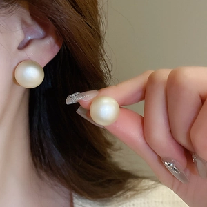 Close-up of matte champagne pearls on elegant geometric studs worn by a model